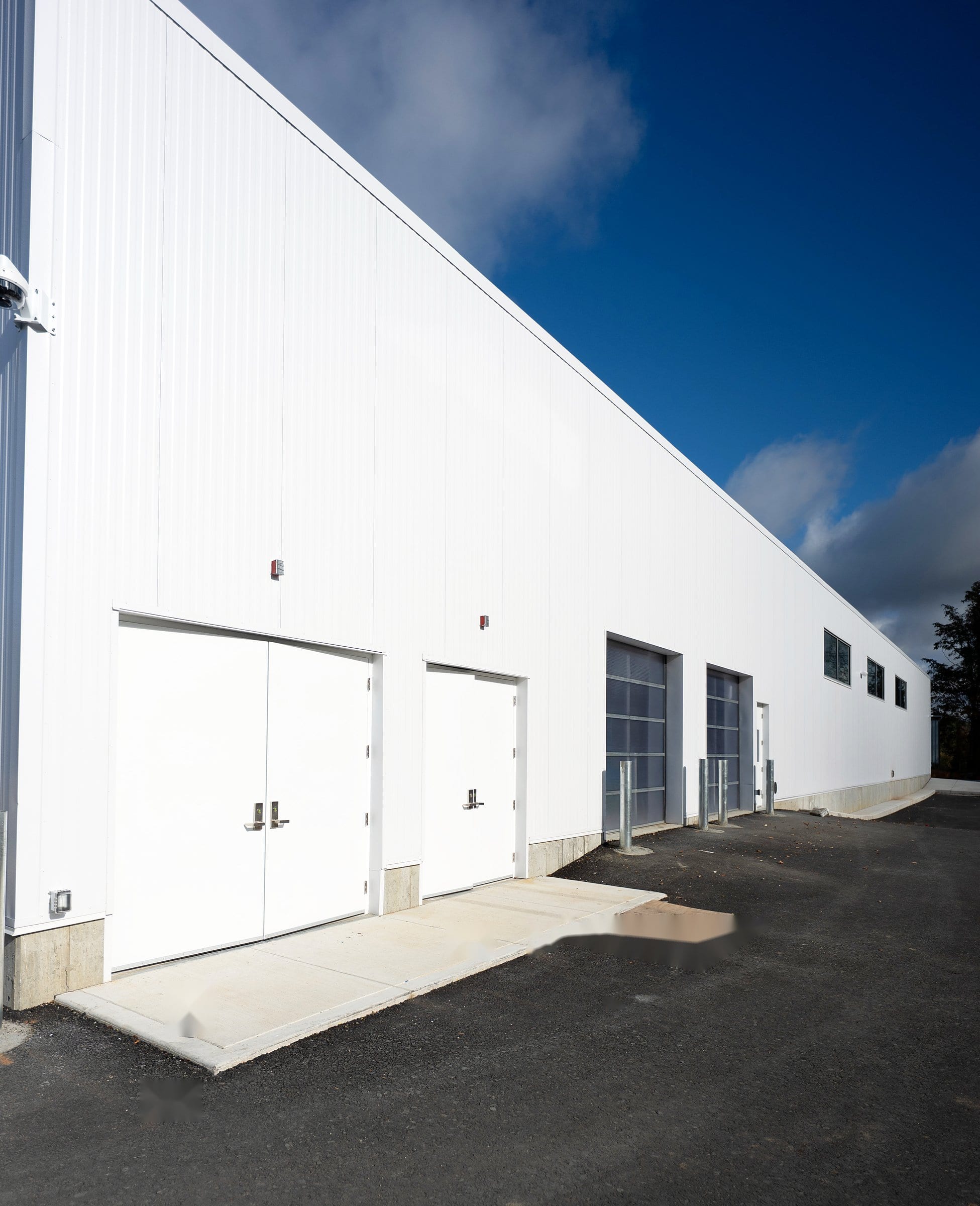 Panel wall running past pairs of white service doors and glazed bay doors along the length of the McGee service building in Lenox, MA