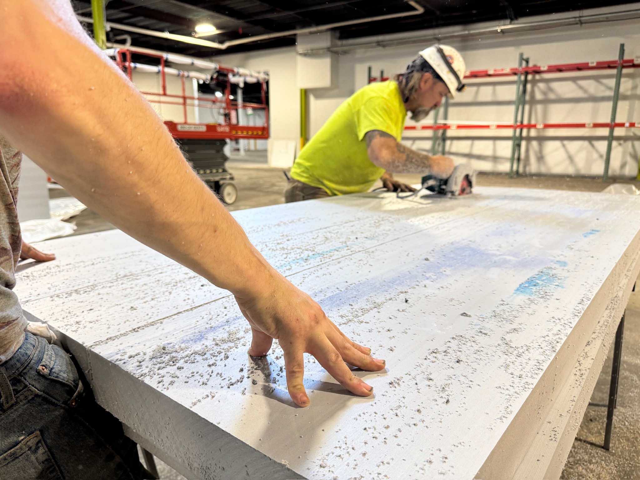 An RSNE crew member cutting an insulated metal panel with a circular saw on a job site
