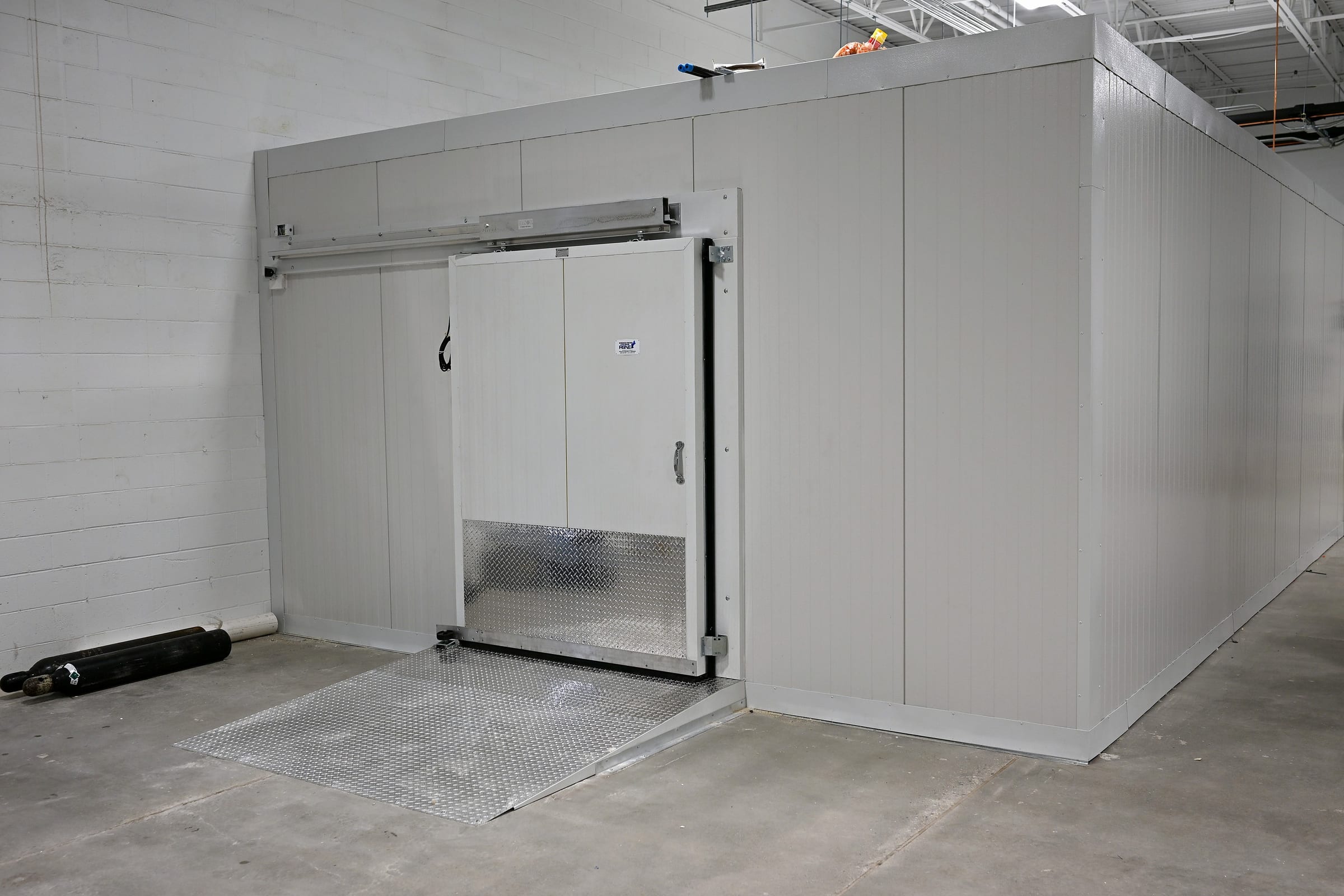 Insulated panel cooler and freezer box built inside the ZeptoMetrix plant in Franklin, MA, RSNE sliding door open over a diamond-plate ramp