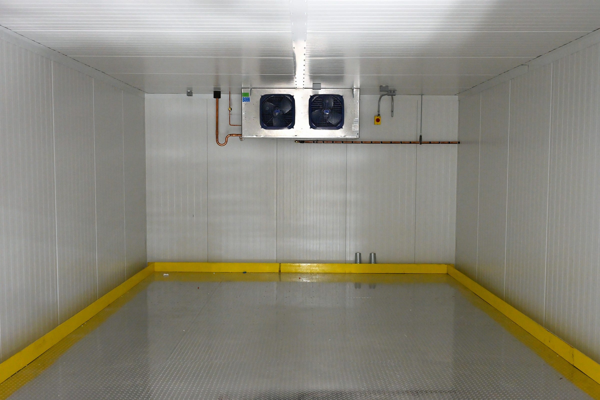 Inside the finished ZeptoMetrix room in Franklin, MA: white panel walls, a ceiling evaporator and a yellow bumper rail around the floor